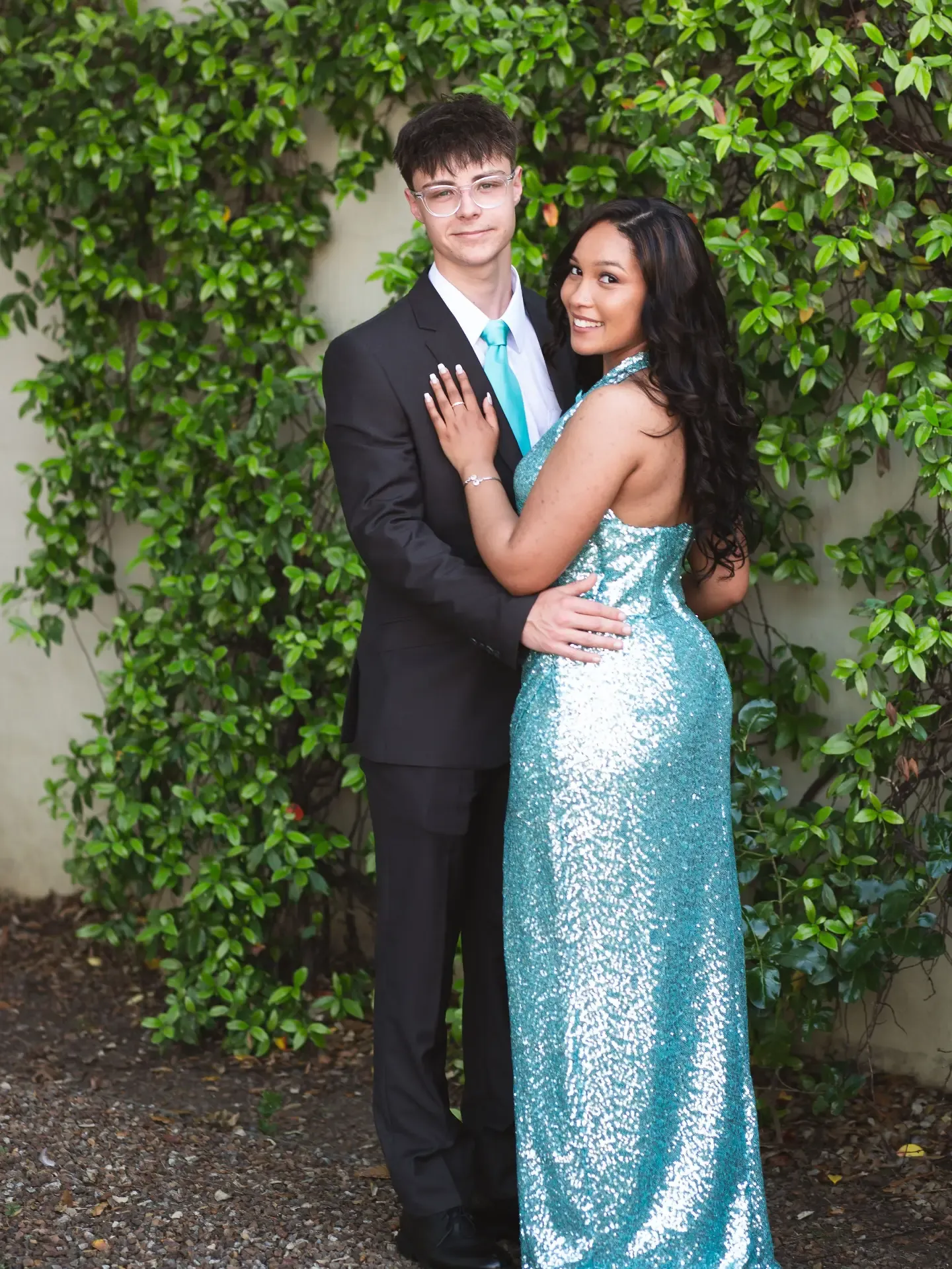 Matric couple posing together against a wall of climbing greenery.