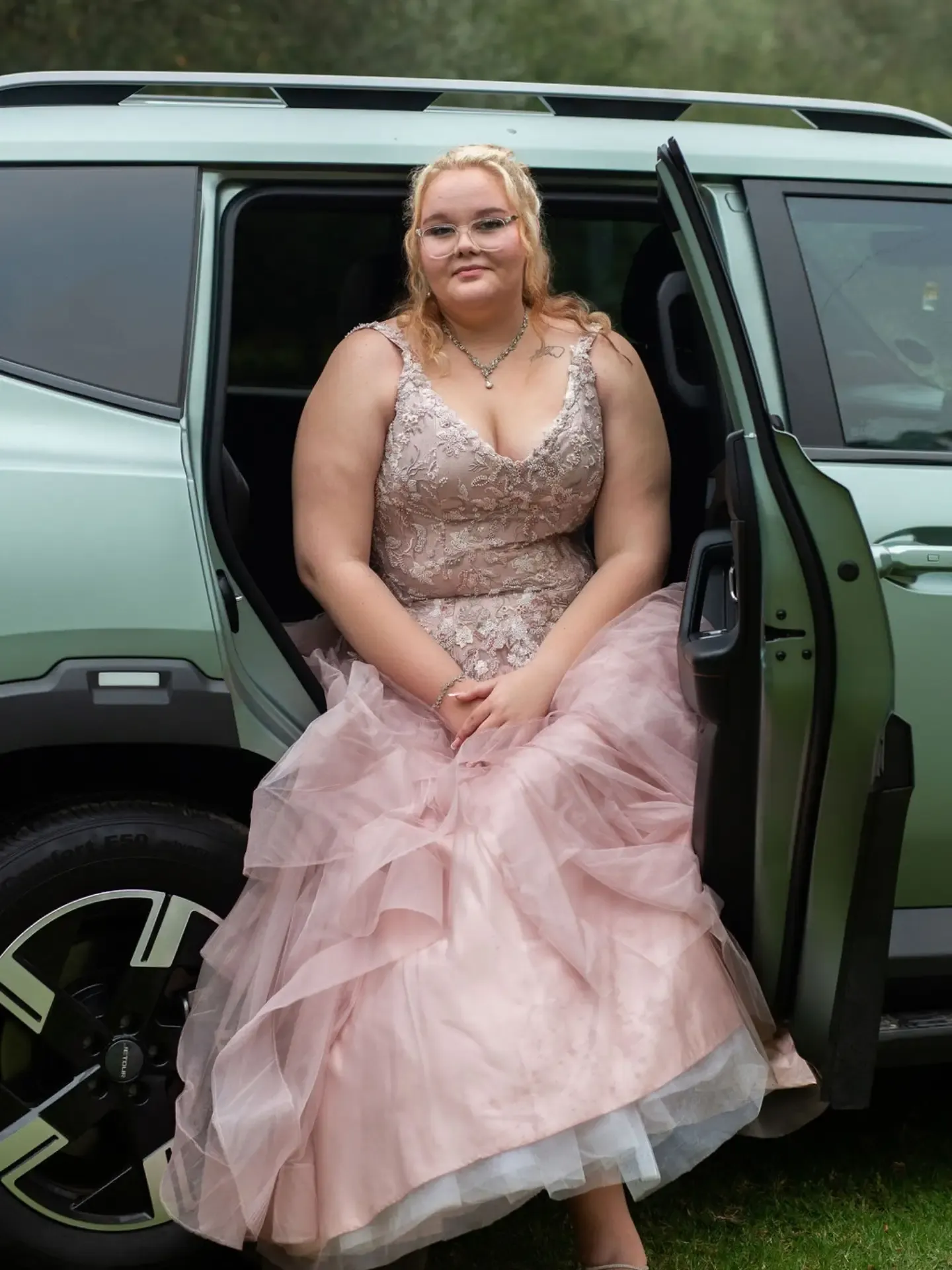 Matriculant in a ball gown seated in the open door of the car before leaving for the dance