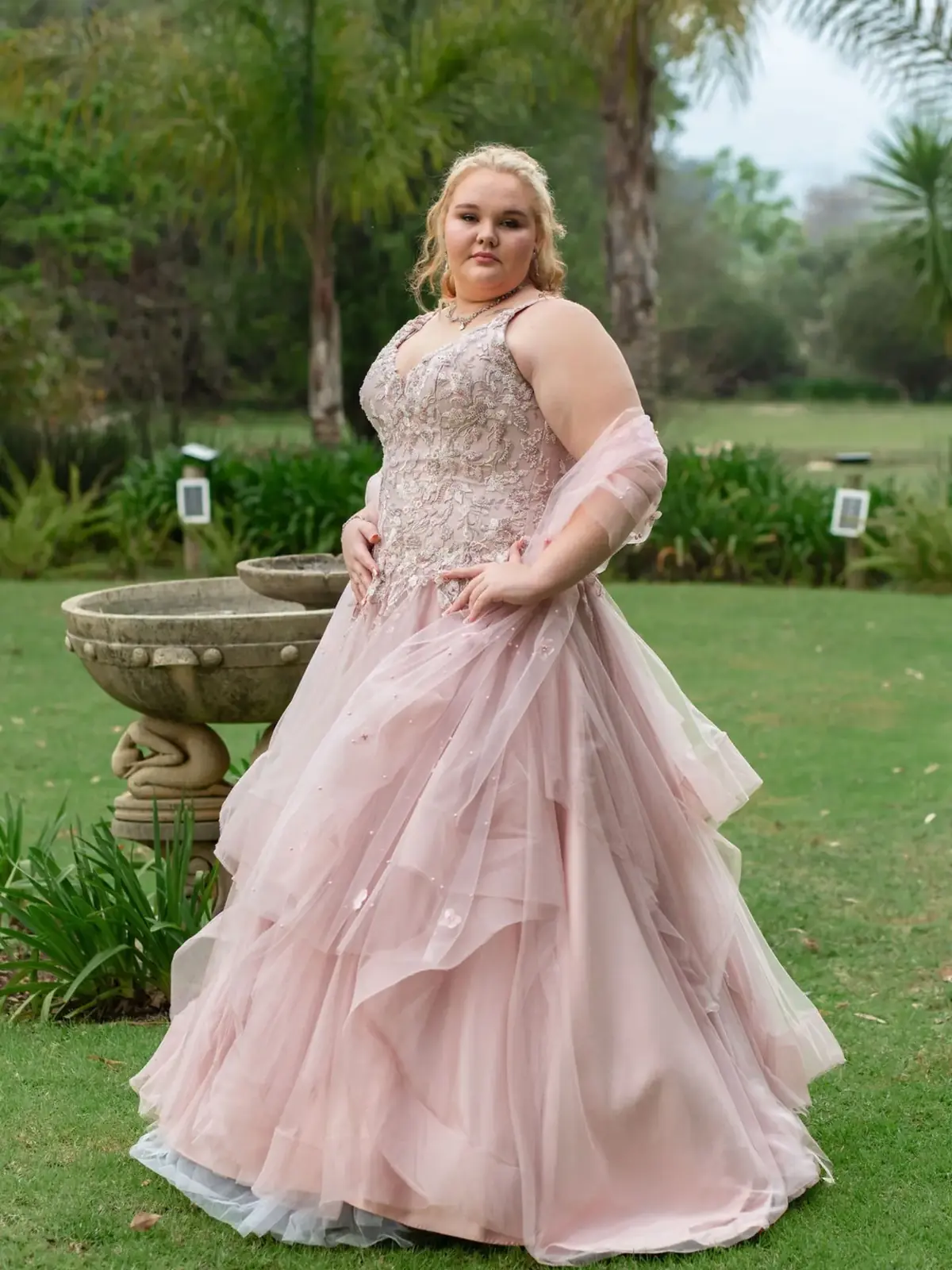 Matric dance photoshoot: matriculant in a blush-pink tulle ball gown standing on a garden lawn